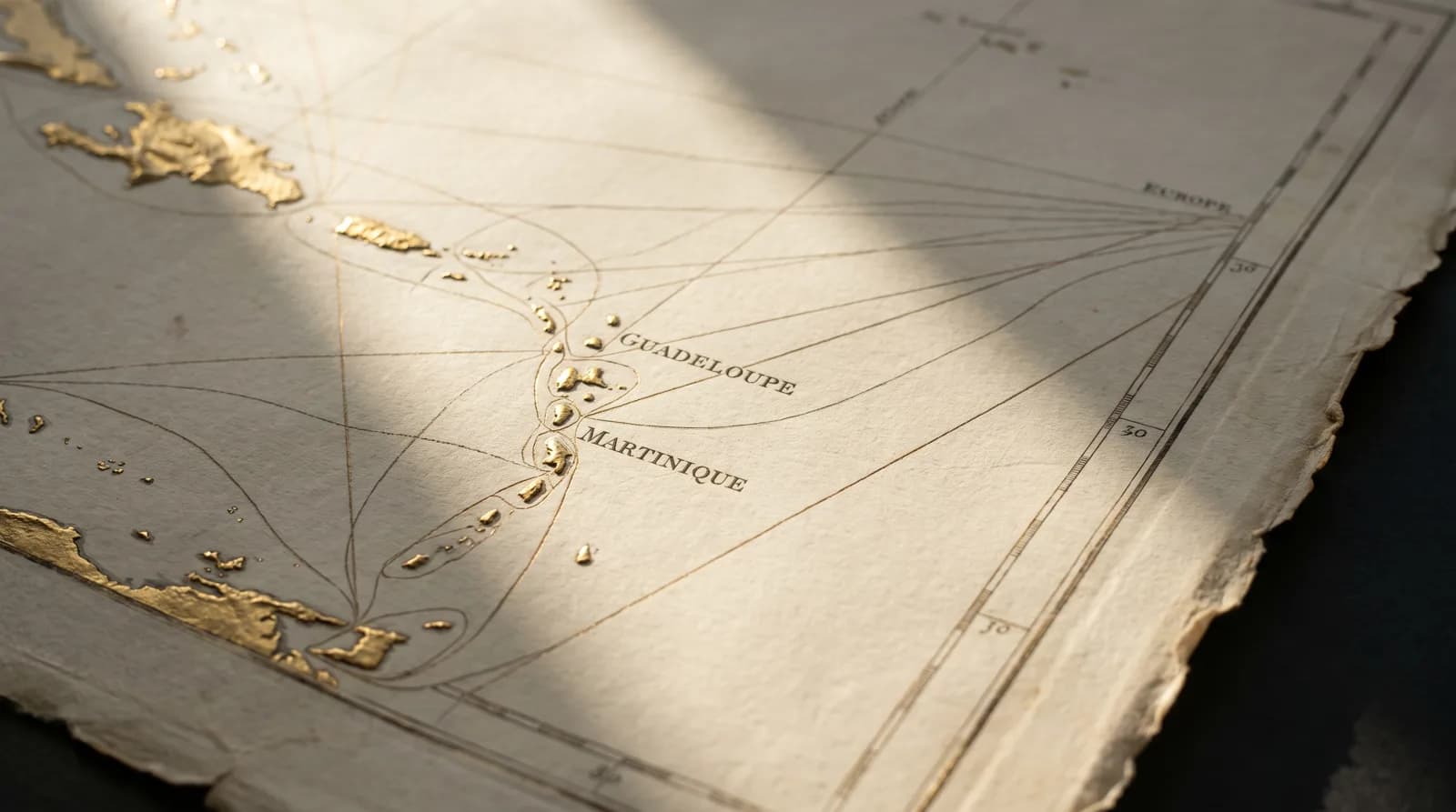 Carte marine ancienne de l'arc antillais, îles rehaussées à la feuille d'or et routes gravées rayonnant vers l'Europe